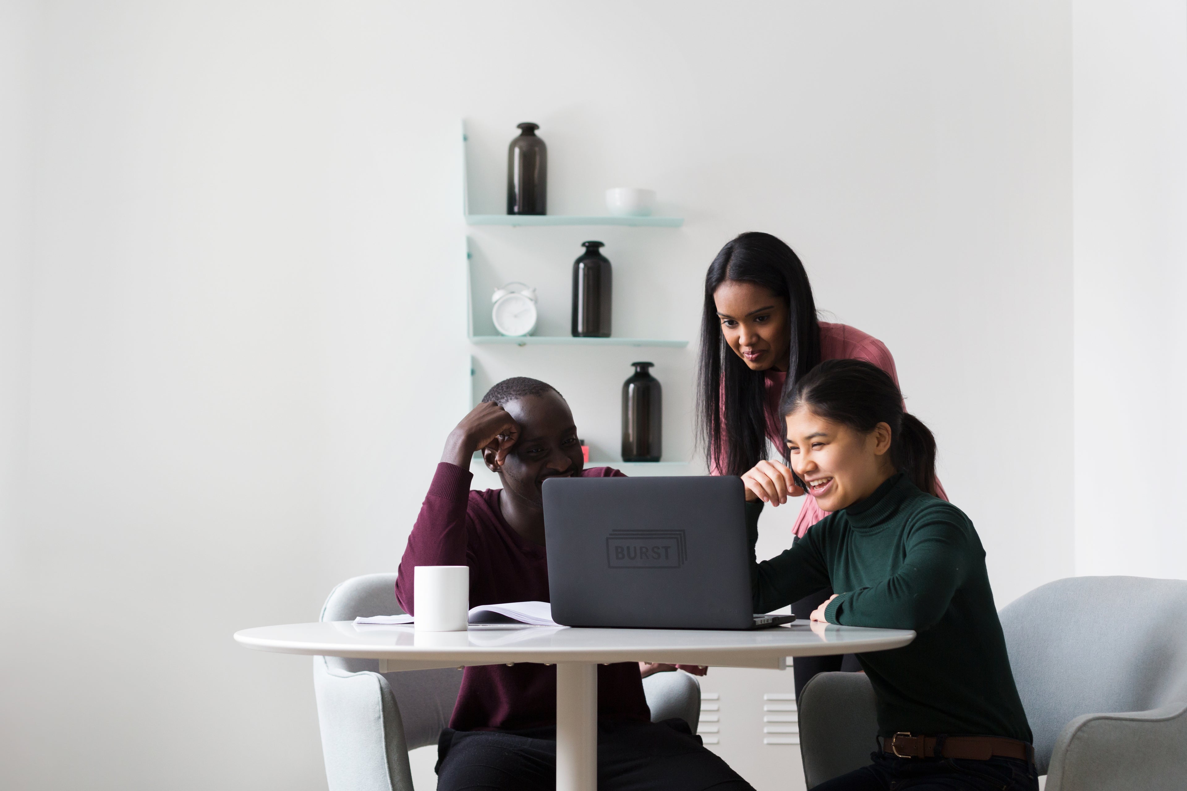 three-individuals-with-laptop-collaborating-at-a-table-in-a-office-setting