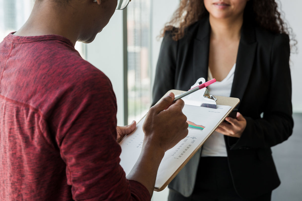 Man holding clipboard discussing procurement and process management in an office
